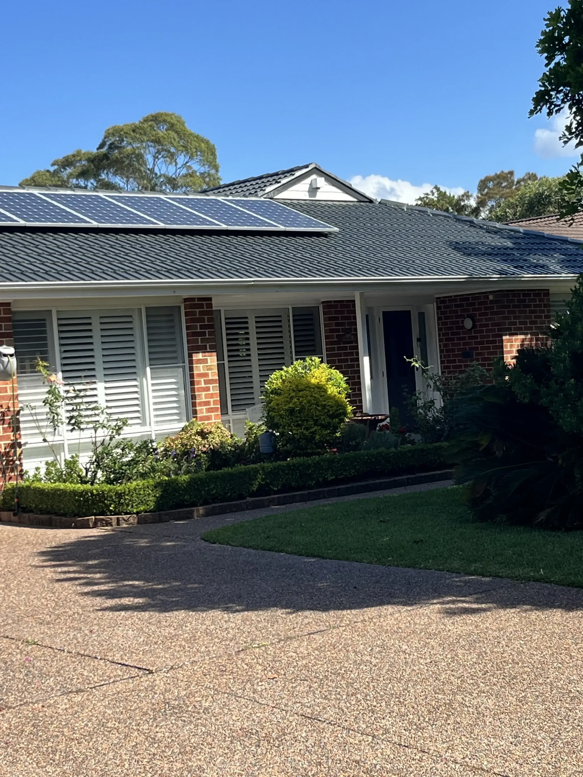 A House With Solar Panels on the Roof and a Driveway — Norwest Roof Restorations In Blue Bay, NSW