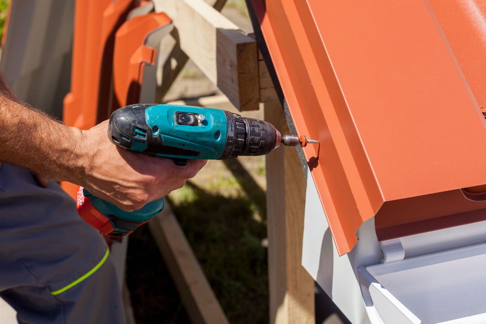A Man Is Using A Drill To Fix A Roof — Norwest Roof Restorations In Blue Bay, NSW