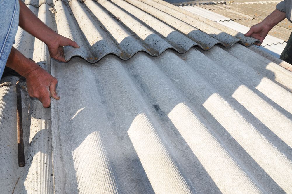 A Man is Working on a Roof With a Hammer — Norwest Roof Restorations In Blue Bay, NSW