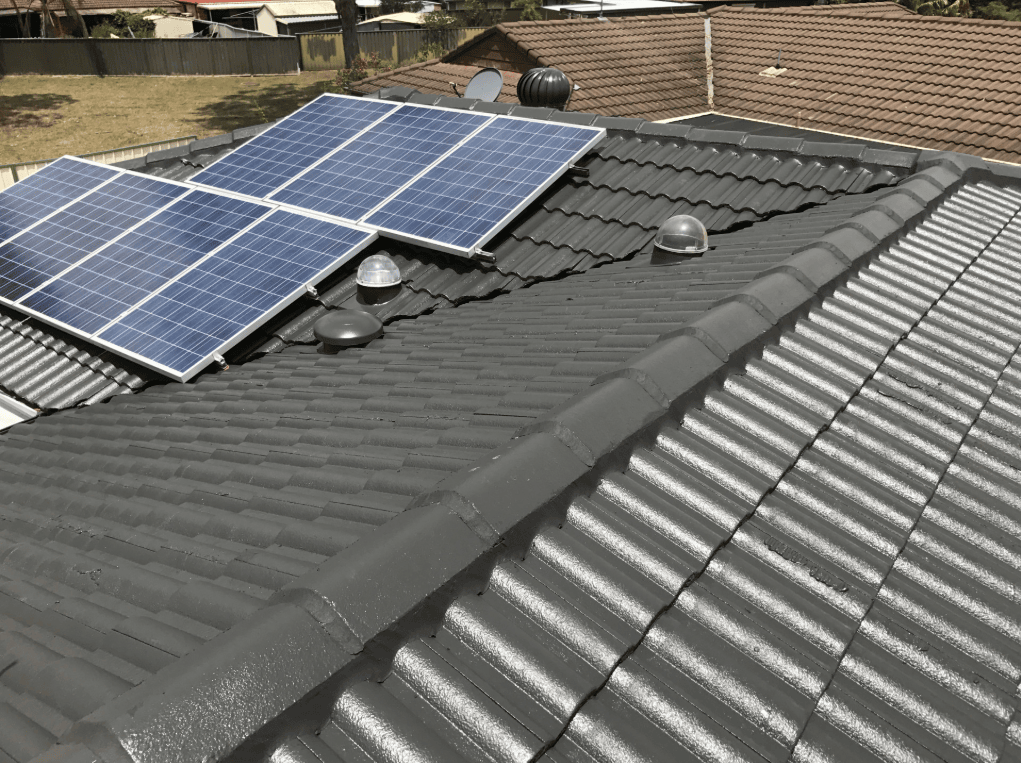 A Row of Solar Panels Sitting on Top of a Tiled Roof — Norwest Roof Restorations In Blue Bay, NSW