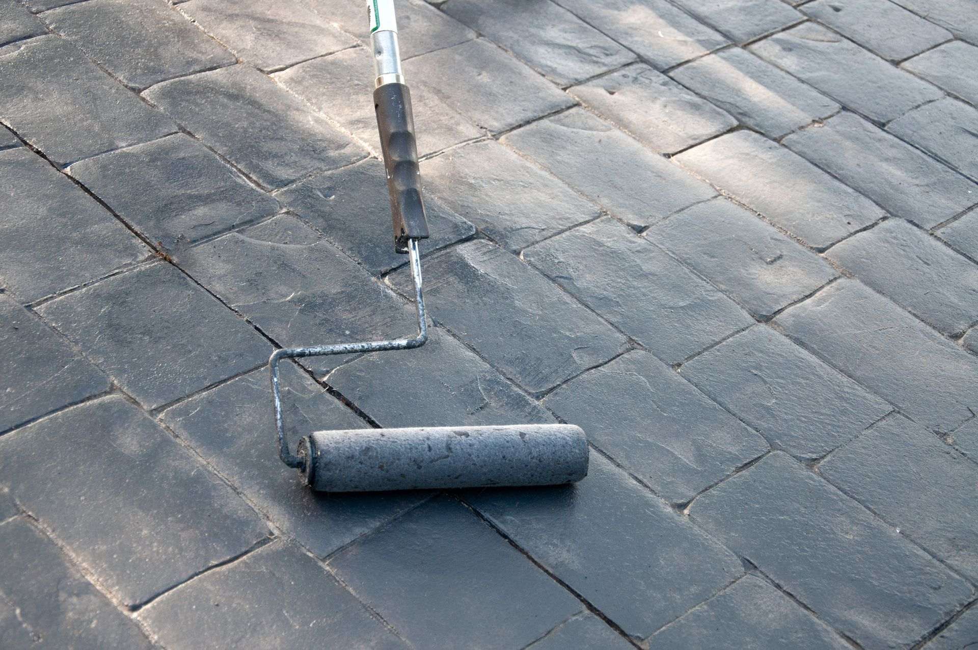 Paint Roller Applying Black Coating to a Surface — Norwest Roof Restorations In Blue Bay, NSW