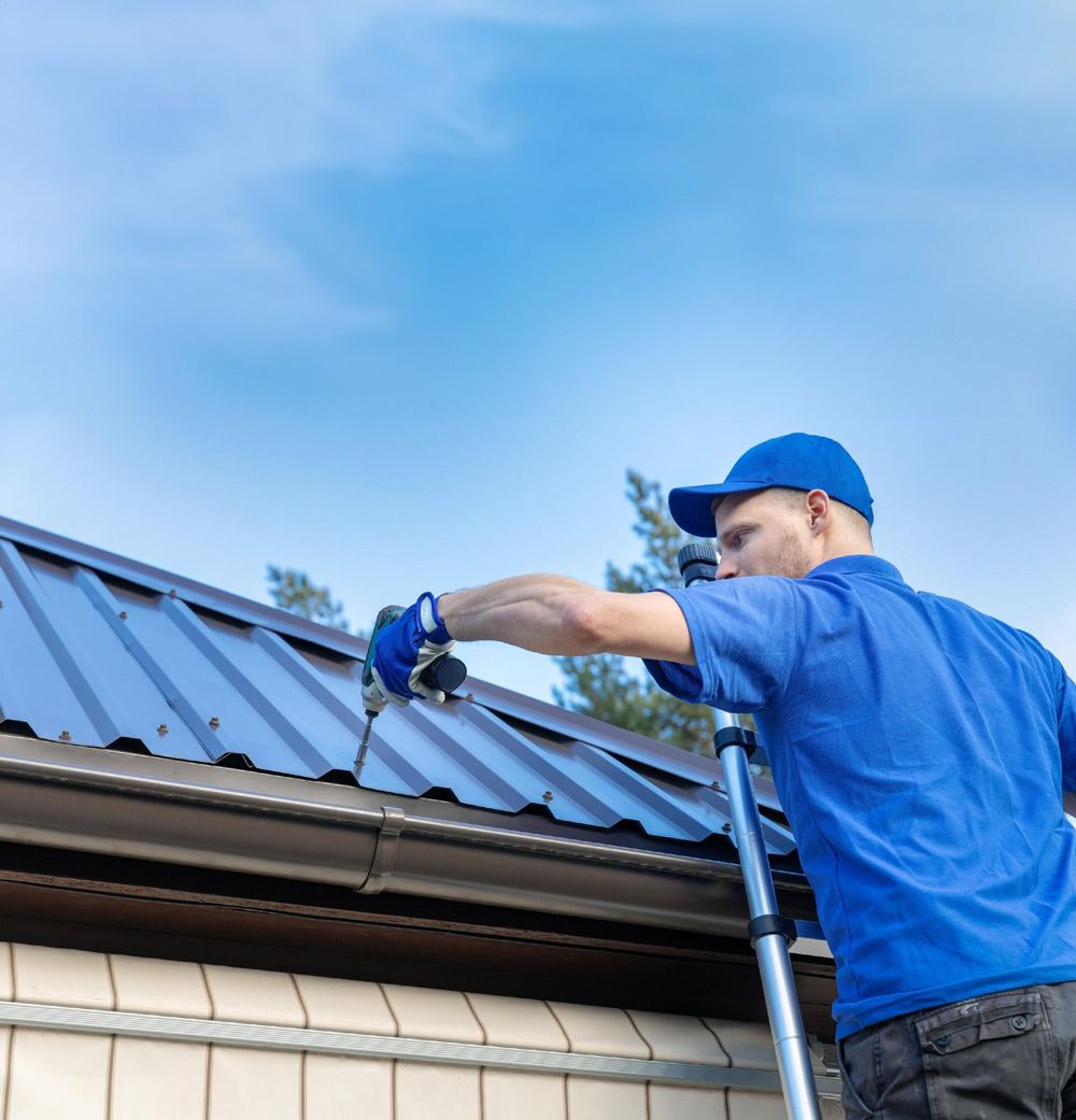 Worker in Blue Uniform Tightening Screws on a Metal Roof — Norwest Roof Restorations In Blue Bay, NSW