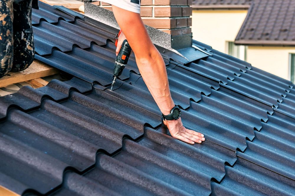 Worker Installing Dark Roof Tiles on a Sloped Roof — Norwest Roof Restorations In Blue Bay, NSW
